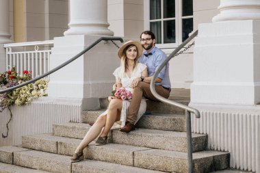 Binanın arka planında şık romantik bir çift. Süslü püslü bir çift bakışlarını başka yöne çeviriyor.