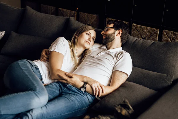 Romantiskt ungt par i vita t-shirts på brun soffa — Stockfoto
