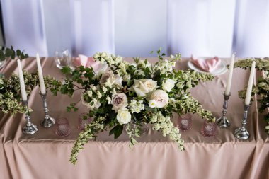 Restoranda taze beyaz güllü gelin ve damat için başkanlık makamının en iyi manzarası. Yeni evliler için lüks düğün ziyafetini kapatın.