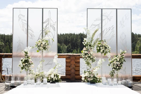 Wedding ceremony with white transparent screens and fresh flowers and candles. Wedding exit ceremony with two screens with feather and white rose
