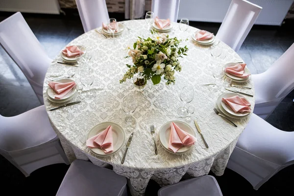 Top view of festive table setting with wine glasses, and fresh flowers. Selebration banquet with pink napkins, white plates and wineglasses in restaurant