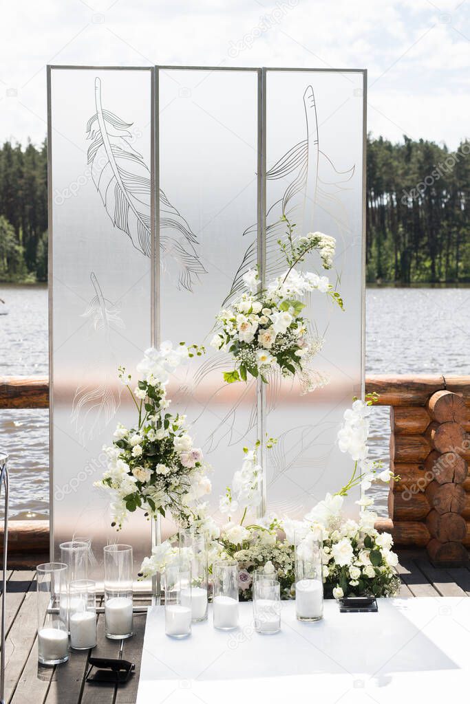 Close up of wedding ceremony with white transparent screens and fresh flowers and candles. Wedding exit ceremony with two screens with feather and white rose