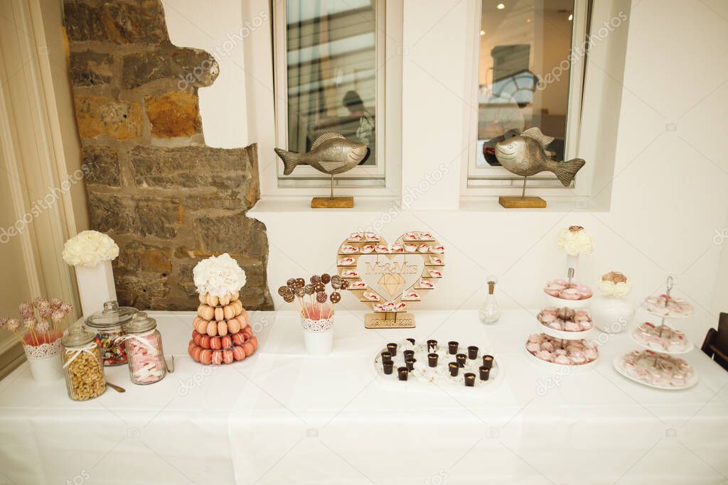 Festive wedding tables with sweets, candies, dessert. Candy bar in pink, brown and beige colors
