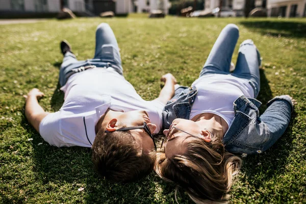 Großaufnahme von stilvollem Paar lächelnd und einander auf grünem Gras liegend — Stockfoto