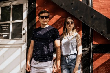 Romantik çift el ele tutuşup gözlerini kaçırıyor. Mutlu adam ve kadın bina geçmişinde