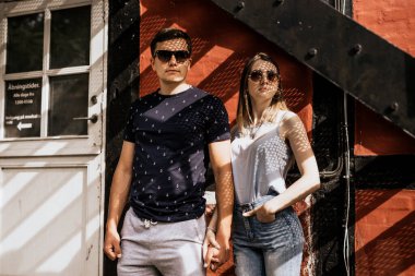 Romantik çift el ele tutuşup gözlerini kaçırıyor. Mutlu adam ve kadın bina geçmişinde