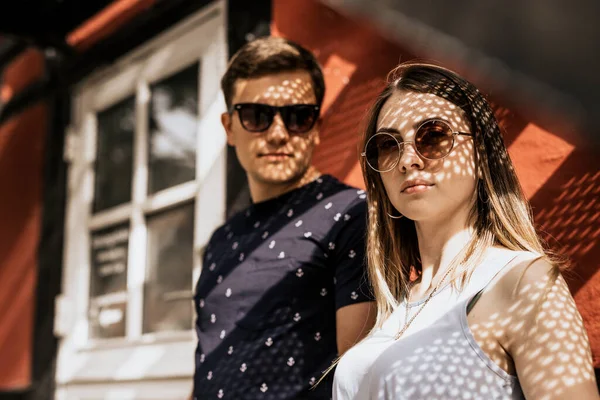 Romantik çiftlere yaklaşın ve güneş ışığının gölgesiyle kameraya bakın. Ciddi bir adam ve kadın bina geçmişinde.