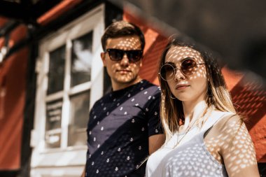 Romantik çiftlere yaklaşın ve güneş ışığının gölgesiyle kameraya bakın. Ciddi bir adam ve kadın bina geçmişinde.