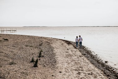 Romantik çift el ele tutuşup sahilde yürüyor. Seyahat yaşam tarzı konsepti