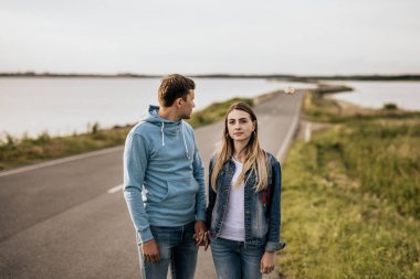 Sahilde dağlarla yürüyen romantik çifti yakından takip edin. Seyahat yaşam tarzı konsepti