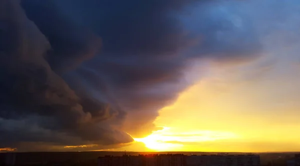 濃い青の暗い雲と明るい黄色の夕日 — ストック写真