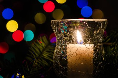 Noel ışıkları ve Evergreen dalları ile çevrili beyaz Noel mum