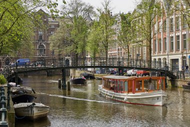Amsterdam Hollanda'da bir kanal üzerinde birçok köprüden biri altında turist teknesi