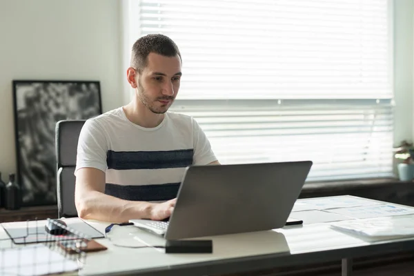 Joven hombre de negocios trabajando en un portátil en su escritorio en la oficina — Foto de Stock