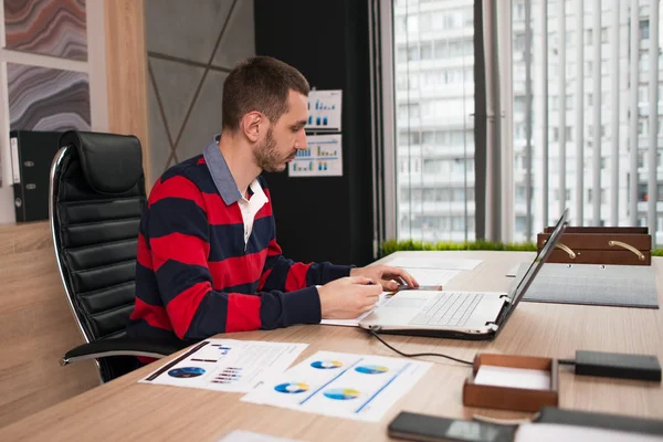 Junger Geschäftsmann arbeitet an einem Laptop an seinem Schreibtisch im Büro — Stockfoto