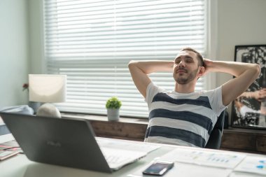 Masada ofiste oturan adam işadamı, ellerini başının arkasına koydu, gözlerini kapattı ve dinleniyor