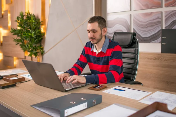 Működő-ra egy laptop, az irodában a pultnál fiatal üzletember — Stock Fotó