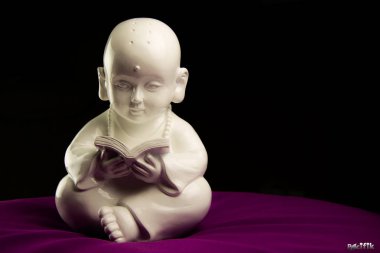 Buda Leyendo En Un Cojin Morado Sobre Fondo Negro