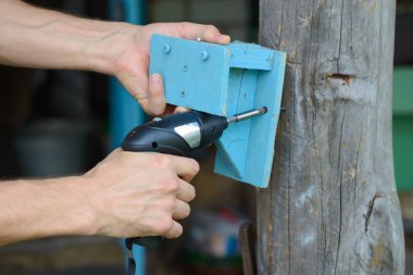 İşçinin arms ahşap raflara bir tornavida ile vidalı olan