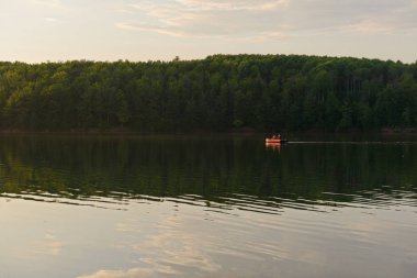 Çift bir yaz akşamı bir gölde bir tekne sürme