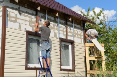 6 Ağustos 2017: Apartman vinil siding ile iki işçi Lehçe. Moskakassy. Chuvashy. Rusya.
