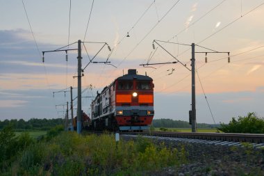Yük treni gün batımında demiryolu ile hareket ediyor