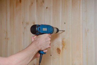 Bir işçi bir matkap ve matkaplar bir ahşap duvar tutar