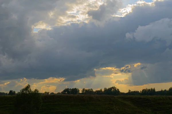 Dark clouds and rays of the sun over a green ravine