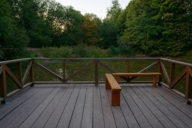 bir çit ve bir yaz akşamı küçük gölet bakan bir Bank ile veranda