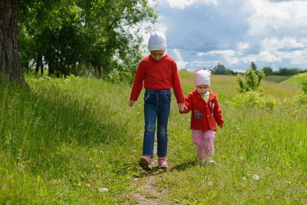 iki kız kardeş el ele tutuşarak yol boyunca yürüyüş