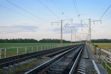 Bir yaz gününün gün batımında yeşil bir vadi üzerinde demiryolu köprüsü