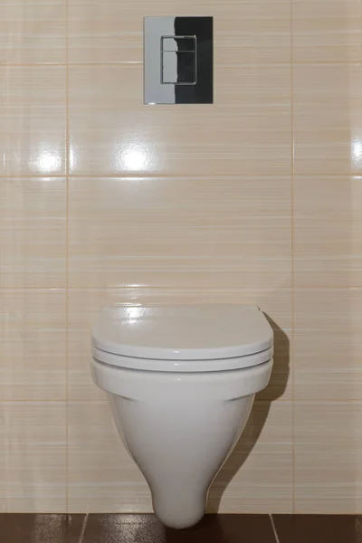 Настінний туалет з гудзиками на бежевій настінній плитці — стокове фото