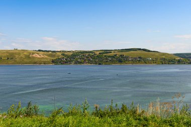 Bir yaz günü geniş bir nehrin kıyısında küçük bir yerleşim yeri.
