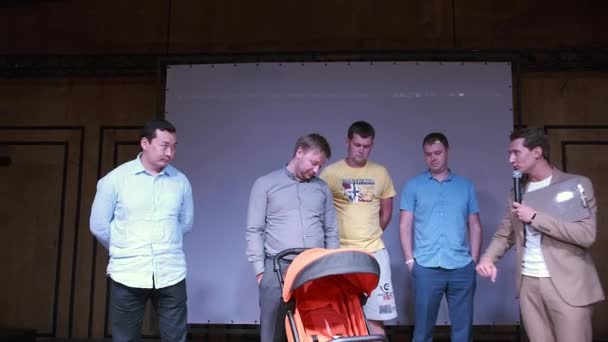 Młodzi i przyszli tatusiowie uczestniczą w konkursie na scenie składania i rozkładania wózka dla niemowląt podczas imprezy masowej — Wideo stockowe