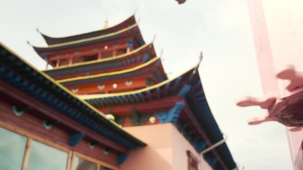 Vídeo em câmera lenta de uma rotação de um tambor rosa de madeira perto de um templo budista — Vídeo de Stock