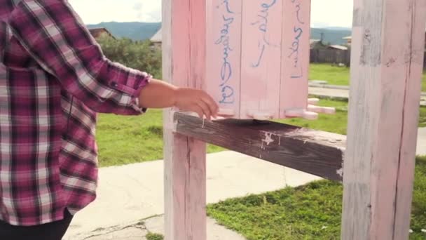 Vídeo en cámara lenta de una niña girando tambores rosados de madera cerca de un templo budista durante la oración — Vídeo de stock