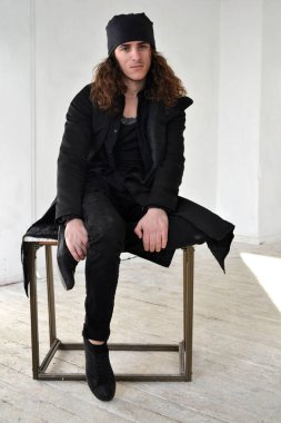 siyah giysiler ve beyaz arka plan bacak bacak masada oturan bir kap uzun kıvırcık saçlı fotoğraf çocuk