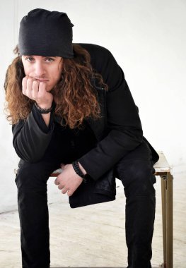 uzun kıvırcık saç siyah elbise ve şapka ile fotoğraf adam üzgün beyaz arka plan oturur