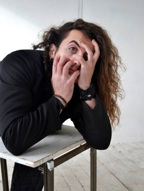 Fotoğraf portre etkileyici adam aktör ile poz siyah giysili uzun kıvırcık saçlı beyaz arka plan eller