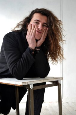 Fotoğraf portre etkileyici adam aktör ile poz uzun kıvırcık saçlı beyaz arka plan eller