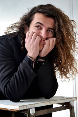 Fotoğraf portre etkileyici adam aktör ile siyah poz içinde uzun kıvırcık saçlı beyaz arka plan eller