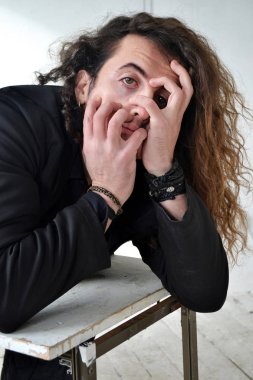 Fotoğraf portre etkileyici adam siyah giysiler ile poz uzun kıvırcık saçlı beyaz arka plan eller