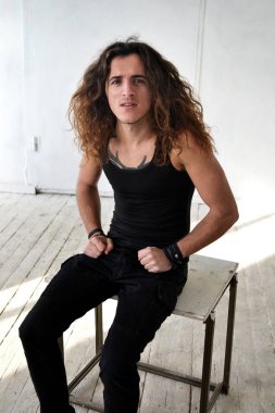 uzun kıvırcık saç ve siyah elbiseli oturan bir adam portresi fotoğraf