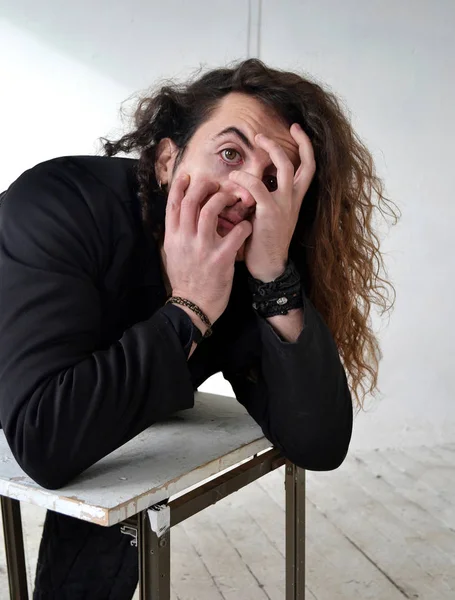 Fotoğraf portre etkileyici adam aktör ile poz siyah giysili uzun kıvırcık saçlı beyaz arka plan eller