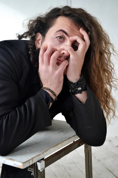 Fotoğraf portre etkileyici adam siyah giysiler ile poz uzun kıvırcık saçlı beyaz arka plan eller