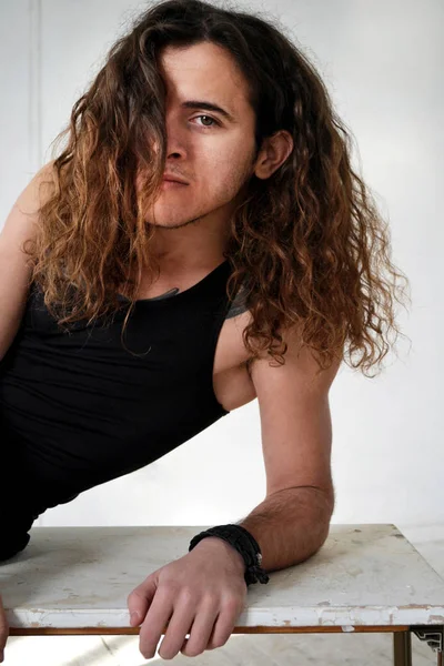 photo portrait of a guy with long curly hair in a black t-shirt