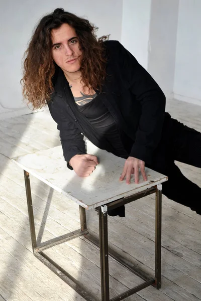 Fotoğraf portre üzgün adam siyah giysili uzun kıvırcık saçlı masanın üzerine eğildi