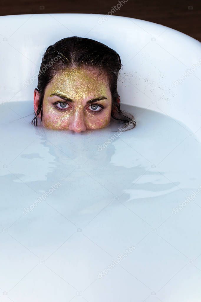photo girl in gold glitter takes a milk bath