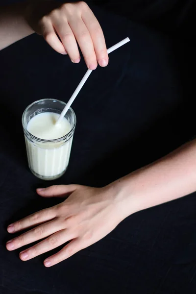 黒い背景にミルクとストローでグラスを持つ手 — ストック写真