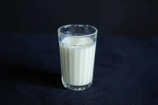 写真のグラス1杯のミルクが黒いテーブルクロスの上に立っている — ストック写真